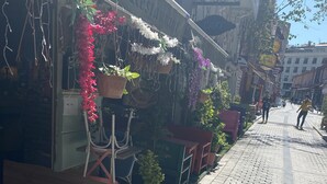 A cobblestone street with a restaurant named "Romantic Mansion" on the right. There are potted plants and outdoor seating along the sidewalk. - Gülhane Hotel (Istanbul)