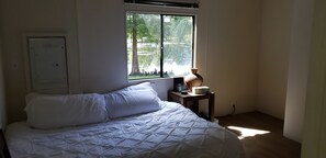 Relax in a serene room with a large bed and a view of the water and trees.