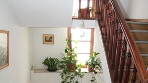 Een houten trap met een leuning, een bankje en potplanten op de overloop.