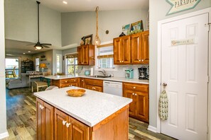 A kitchen with wooden cabinets, a white countertop, a dishwasher, and a hanging light fixture. - Island In The Sun - 3BR Townhouse with Ocean & Sound Views! (North Topsail Beach)