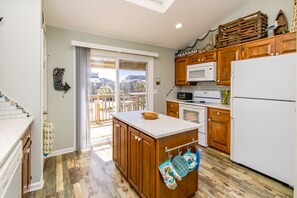 A kitchen with wooden cabinets, a white refrigerator, a microwave, and a stove. There is a sliding glass door leading to a balcony.