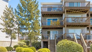 A multi-story residential building with balconies, a staircase, and a view of the surrounding area. - Island In The Sun - 3BR Townhouse with Ocean & Sound Views! (North Topsail Beach)