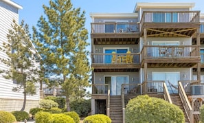 A multi-story residential building with balconies, a staircase, and a view of the surrounding area. - Island In The Sun - 3BR Townhouse with Ocean & Sound Views! (North Topsail Beach)