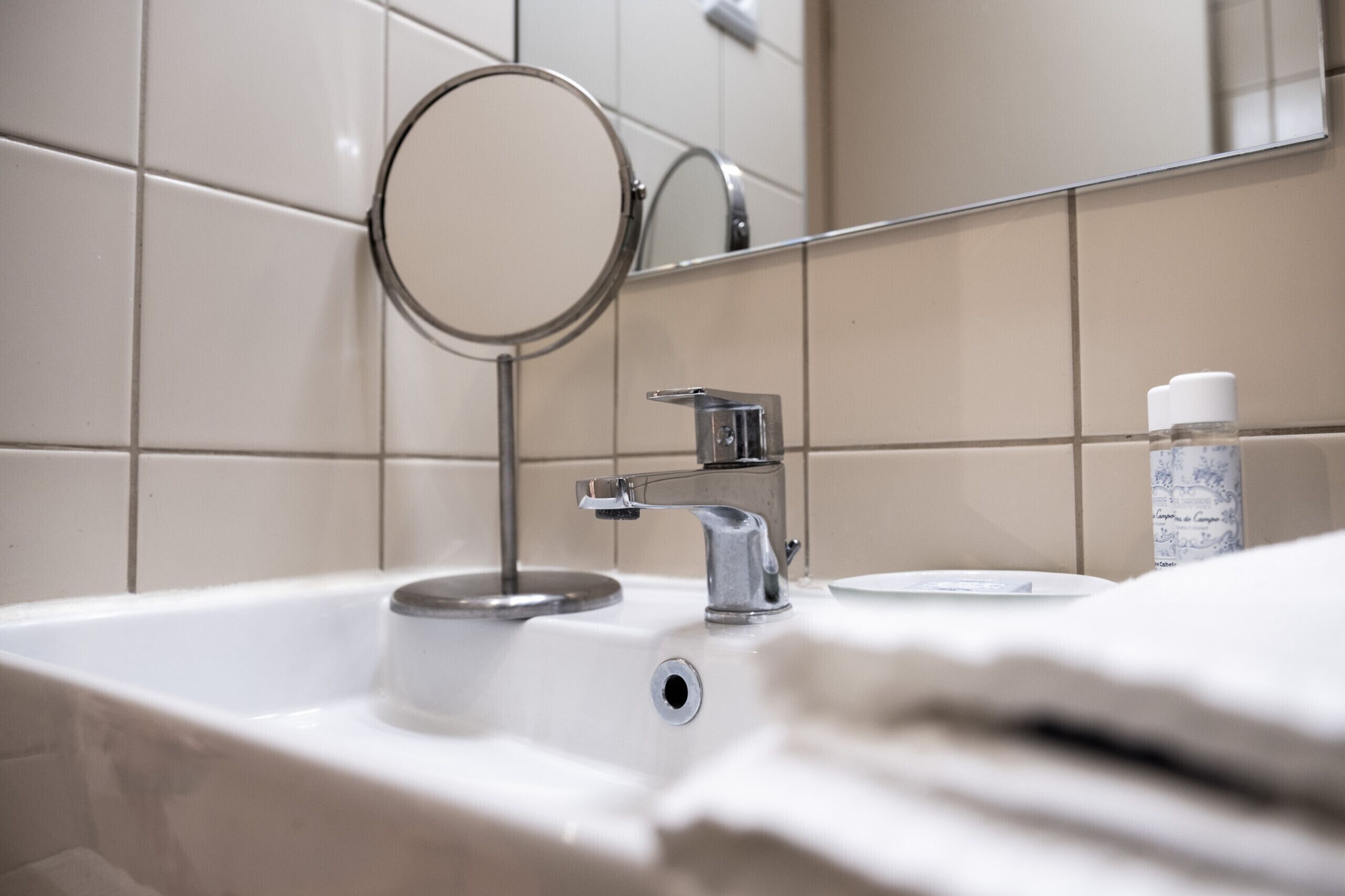 A bathroom with a sink, mirror, and toiletries.