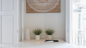 Un escritorio blanco con dos plantas en macetas, un control remoto y un adorno de pared.