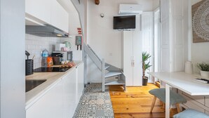 Una cocina pequeña con salpicadero de azulejos, encimera de madera, estufa y microondas.