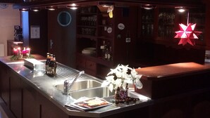A bar area with a wooden bar top, a sink, and a decorative paper lantern. - Landhotel Elterlein (Elterlein)