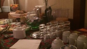 A breakfast table with various dishes, glasses, and a vase of flowers. - Landhotel Elterlein (Elterlein)