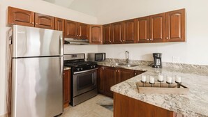 Una cocina con armarios de madera, electrodomésticos de acero inoxidable, encimera de granito y pileta integrada.