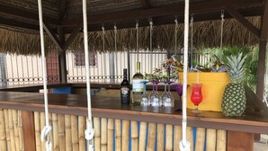 Una zona de bar con fondo de bambú, cuerdas colgantes y una piña.