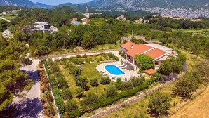 Une propriété résidentielle dotée d’une piscine, entourée d’une végétation luxuriante et avec des montagnes en toile de fond.