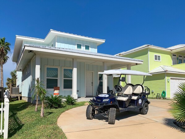 A modern two-story house with a golf cart parked in the driveway. - Golf Cart Included, Shared Pool, Hot Tub, Boardwalk to Beach, Pet Friendly (Port Aransas)