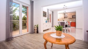 Un apartamento moderno con comedor, cocina y un balcón con vista a zonas verdes.