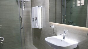 A modern bathroom with a glass shower enclosure, a white sink, and a mirror. - Kadny Court by Citi Apartments (Dansoman)