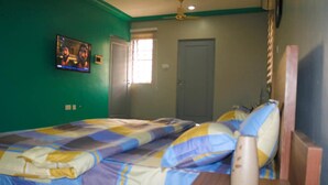 A bedroom with a bed, a nightstand, a vase, and a ceiling fan. - Kadny Court by Citi Apartments (Dansoman)