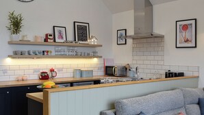 A modern kitchen with a built-in island, a microwave, and a gas stove. - 1 bedroom accommodation in Balcary, near Auchencairn (Balcary, near Auchencairn)