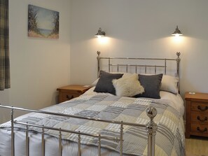A bed with a metal frame, two bedside tables, and wall-mounted lights. - 1 bedroom accommodation in Balcary, near Auchencairn (Balcary, near Auchencairn)