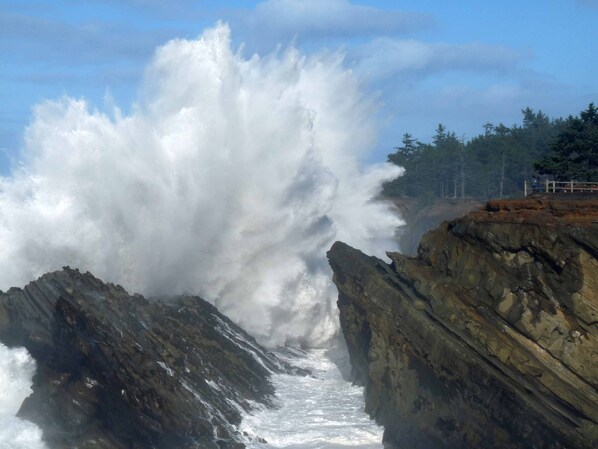 A rocky coastline with a large wave crashing against the rocks.