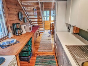 Une cuisine étroite avec un plancher en bois, un coin repas et un escalier menant à l’étage supérieur.