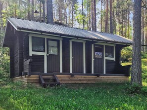A cabin with a metal roof, wooden siding, and a front porch with steps. - Kiviranta by Interhome (Savonlinna)