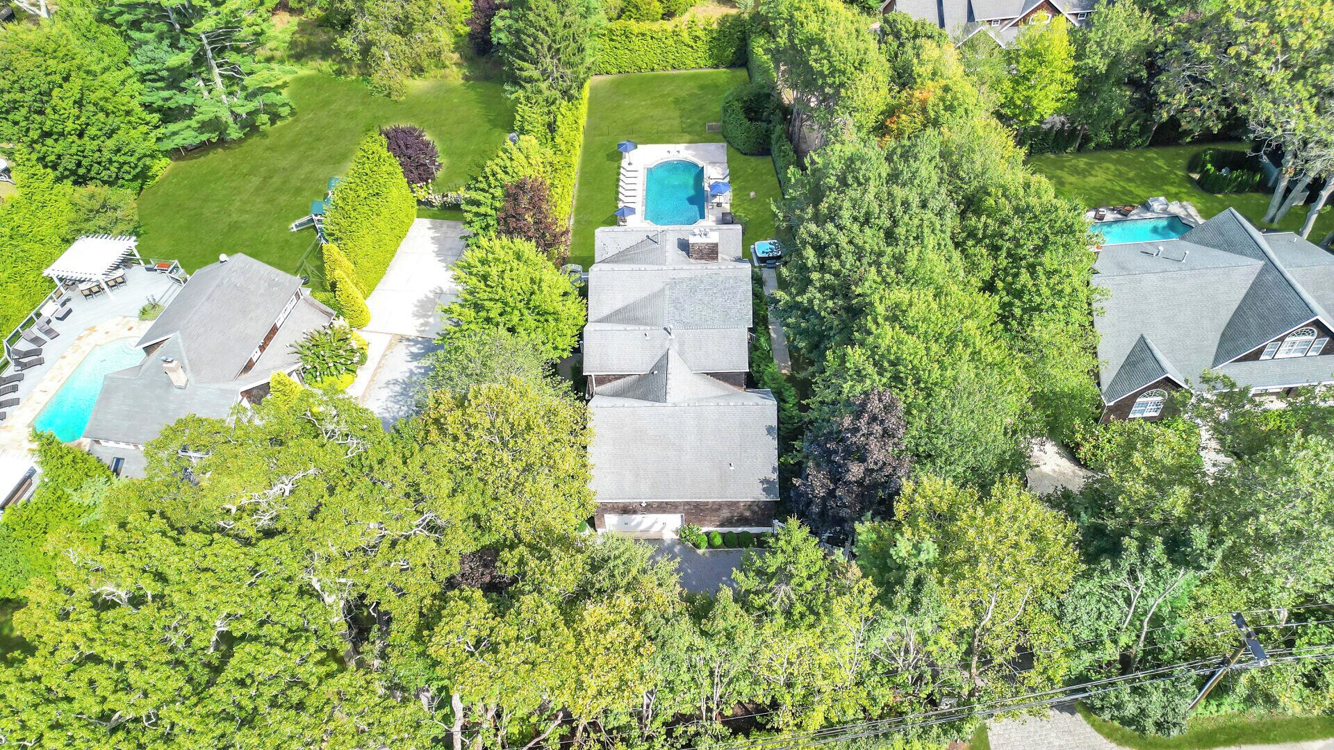 An aerial view of a residential area with multiple houses, a swimming pool, and a well-maintained lawn.
