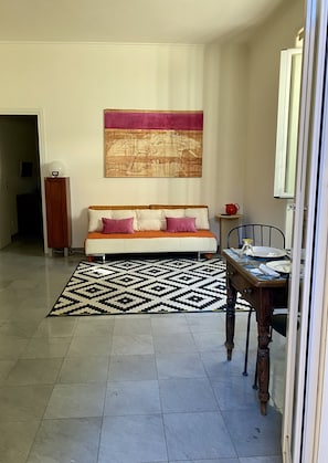 A living room with a sofa, a dining table, and a patterned rug. - - Vatican garden apartment (Roma)
