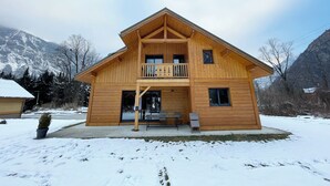 A two-story wooden cabin with a balcony, a covered entrance, and a view of snow-covered mountains. - BOURG D'OISANS/ALPE d'HUEZ ★ CHALET Bois & Nature with panoramic view (LE BOURG D'OISANS)