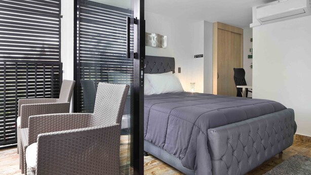 Une chambre à coucher comprenant un lit, une chaise et une porte-fenêtre coulissante donnant sur un balcon.
