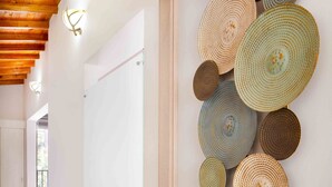Un couloir avec un plafond en bois, un tableau blanc et un mur décoré de paniers tressés de forme circulaire.