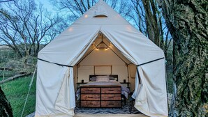 A tent with a bed and storage drawers inside, surrounded by trees. - Sixties Nostalgia - Rhele's Roost at Silver Lake Dunes (Mears)