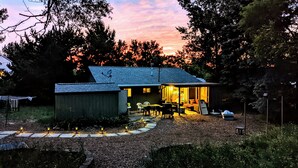 A small house with a porch, a dining area, and a visible kitchen area. - Sixties Nostalgia - Rhele's Roost at Silver Lake Dunes (Mears)