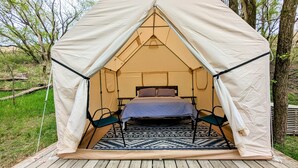 A tent with a bed inside, surrounded by a patterned rug and wooden deck. - Sixties Nostalgia - Rhele's Roost at Silver Lake Dunes (Mears)