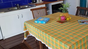 A kitchen with blue tiles, a wooden table with a plaid tablecloth, and a fruit bowl. - Large Studio near the Salines beach, one of the most beautiful in Martinique (Sainte Anne)