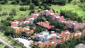 An aerial view of a residential area with colorful houses, a swimming pool, and a road. - Large Studio near the Salines beach, one of the most beautiful in Martinique (Sainte Anne)