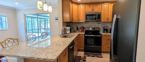 A kitchen with granite countertops, wooden cabinets, a stainless steel refrigerator, and a built-in oven.