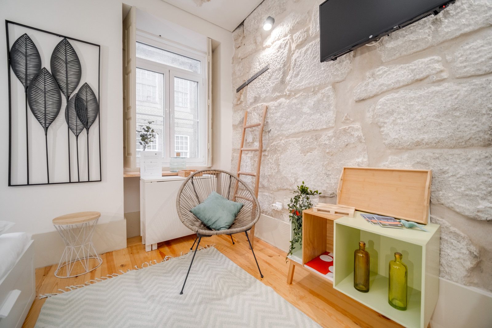 Una sala de estar moderna con una pared de piedra, un sillón de mimbre, un mueble de madera con botellas y un ventanal grande.