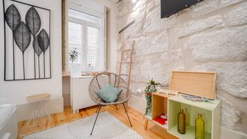 Una sala de estar moderna con una pared de piedra, un sillón de mimbre, un mueble de madera con botellas y un ventanal grande.