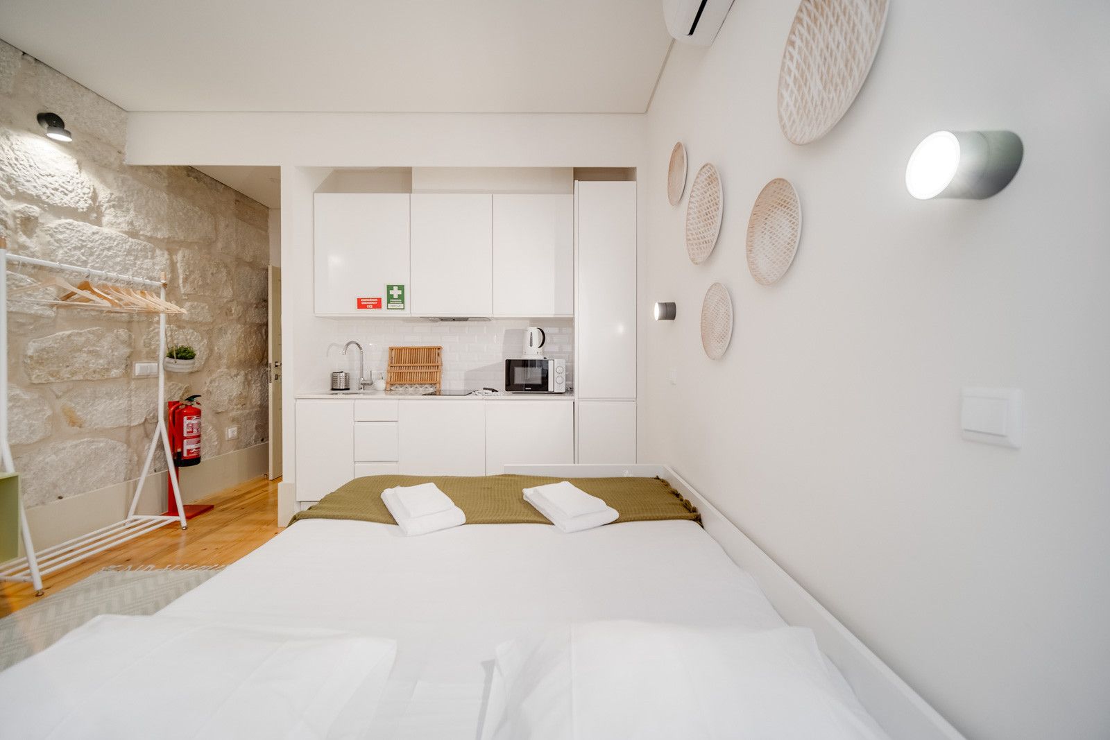 Ein modernes Hotelzimmer mit Bett, einer Küchenzeile und einer Steinwand.