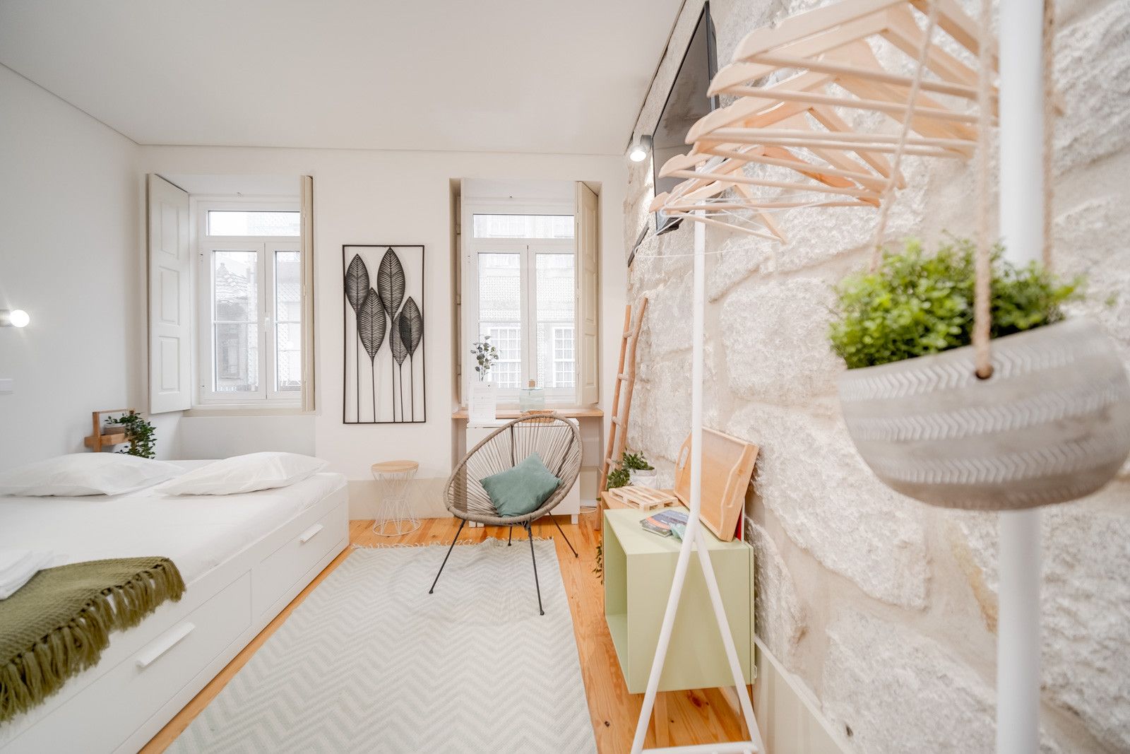 Un dormitorio moderno con una cama, una silla, una planta colgante y obras de arte en la pared.