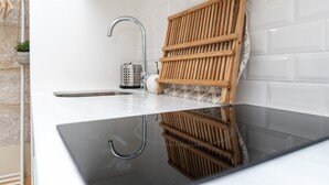 Une cuisine moderne dotée d’un évier en acier inoxydable, d’une étagère en bois et d’un dosseret de carrelage blanc.