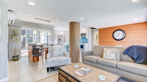 Una sala de estar moderna con sofá, sillón, mesa de centro y un comedor con sillas y mesa.