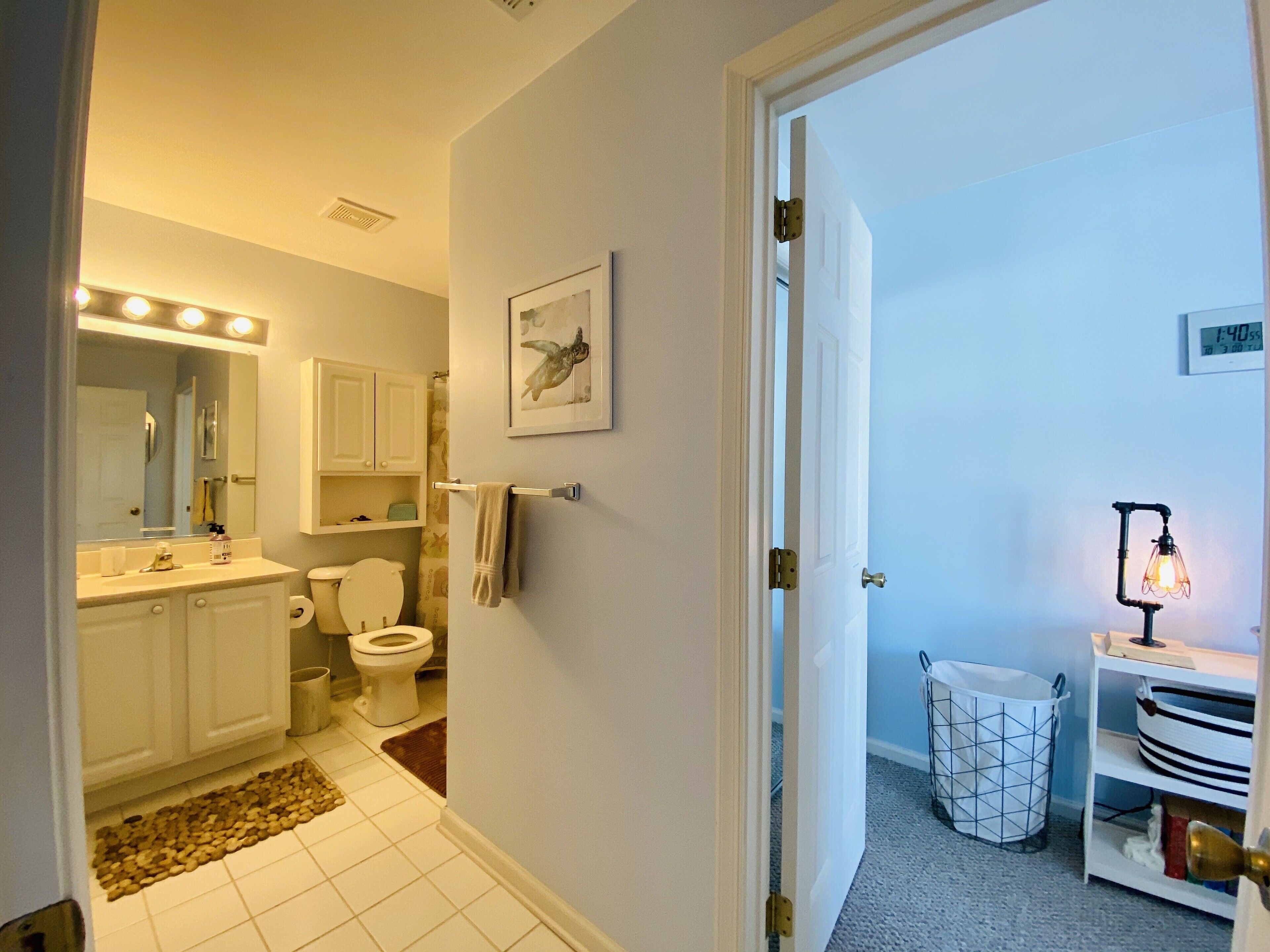 A bathroom with a toilet, sink, mirror, and towel rack.