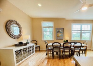A dining area with a table, chairs, a decorative mirror, and a ceiling fan.
