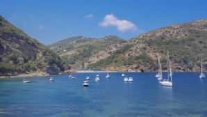 A coastal area with clear blue water and boats anchored near the shore.