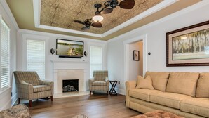 Una sala de estar con chimenea, dos sillones, un sofá y un ventilador de techo.