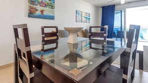 A dining area with a glass-top table, dark wooden chairs, and a modern ceiling fan. - Maho Beach House: Sunset Suite, 1-Bedroom (Maho)