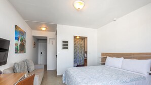 Et hotelværelse med seng, skrivebord, stol, fjernsyn og et maleri på væggen.