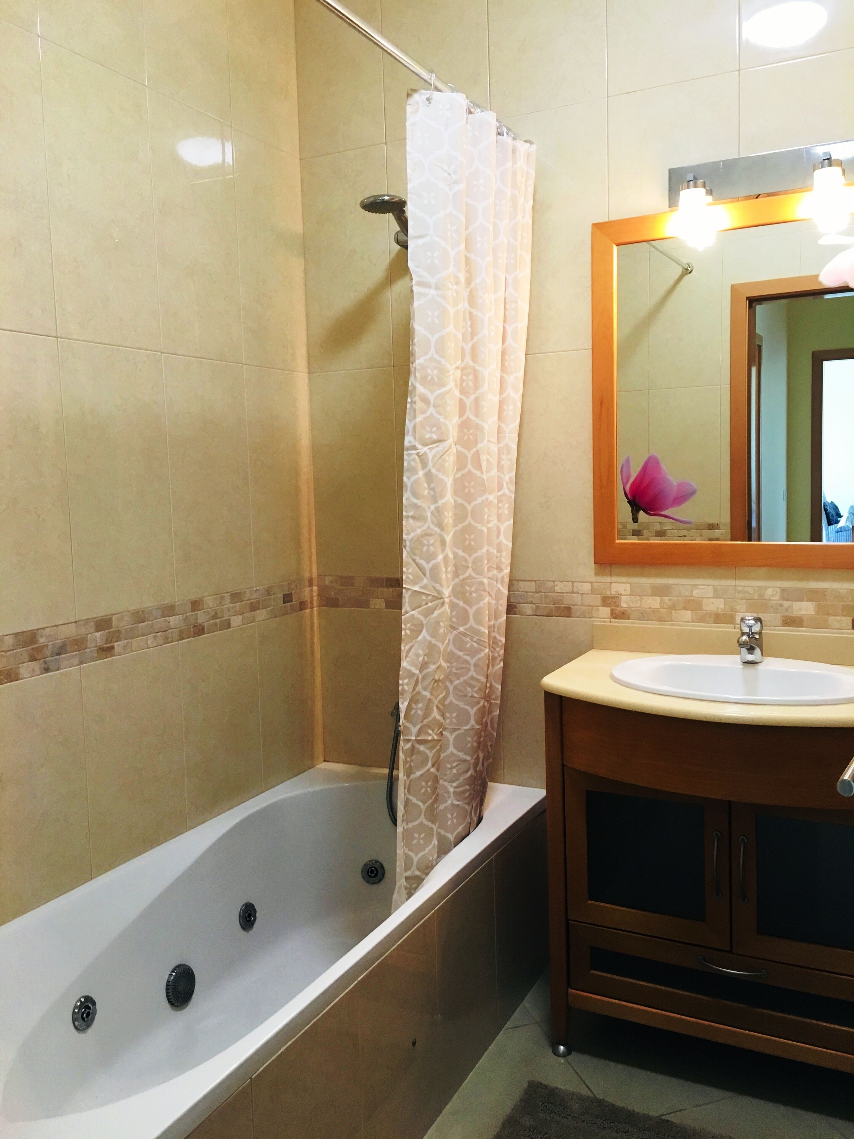 A bathroom with a bathtub, a sink, a mirror, and a shower curtain.
