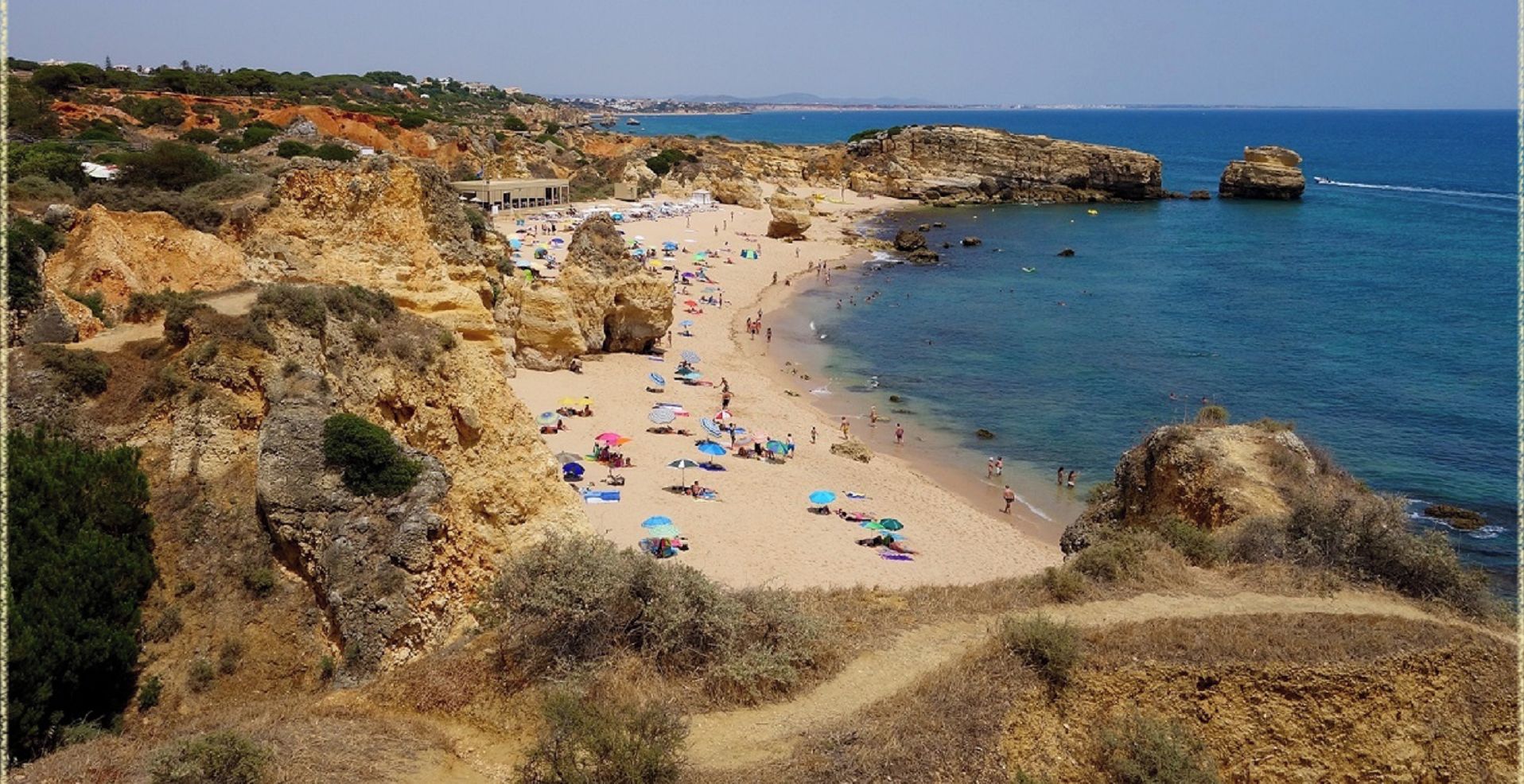A coastal beach with rocky cliffs and a sandy shore.