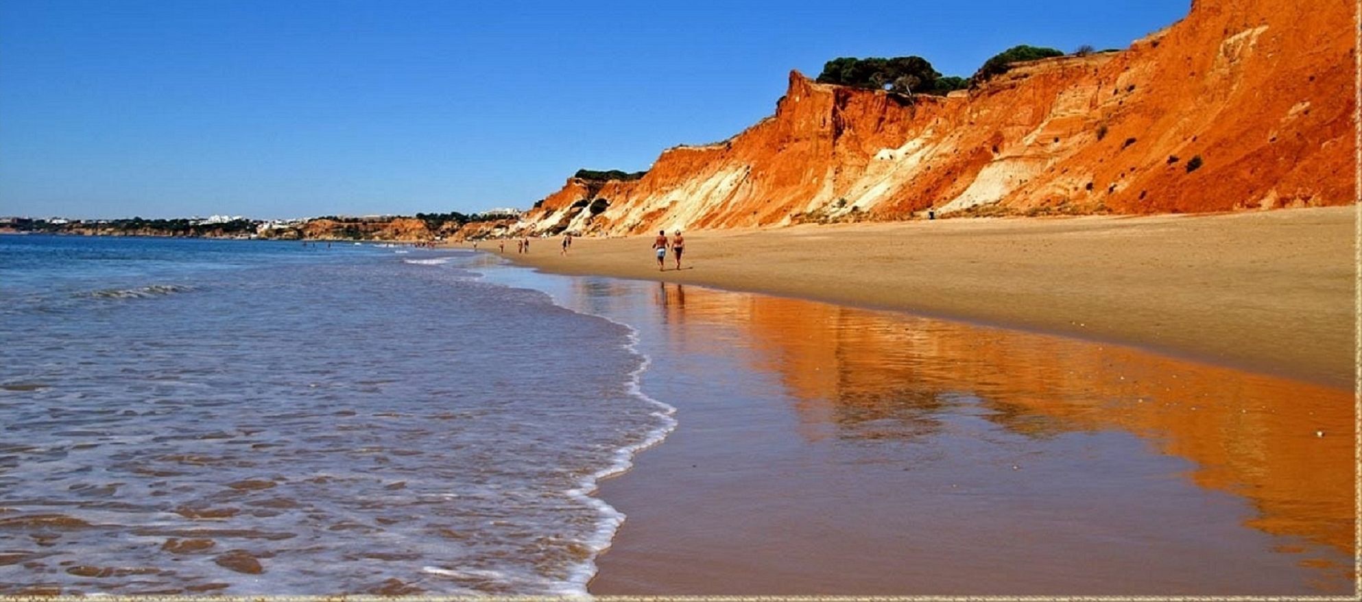 Praia de Falesia, 7km von Encosta entfernt, mit einem Sandstrand, sanften Wellen und einem Felsplateau im Hintergrund.